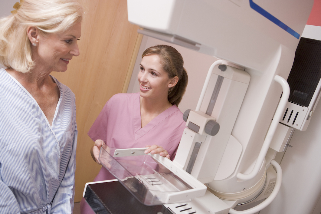 Nurse assisting lady about to have a mammogram